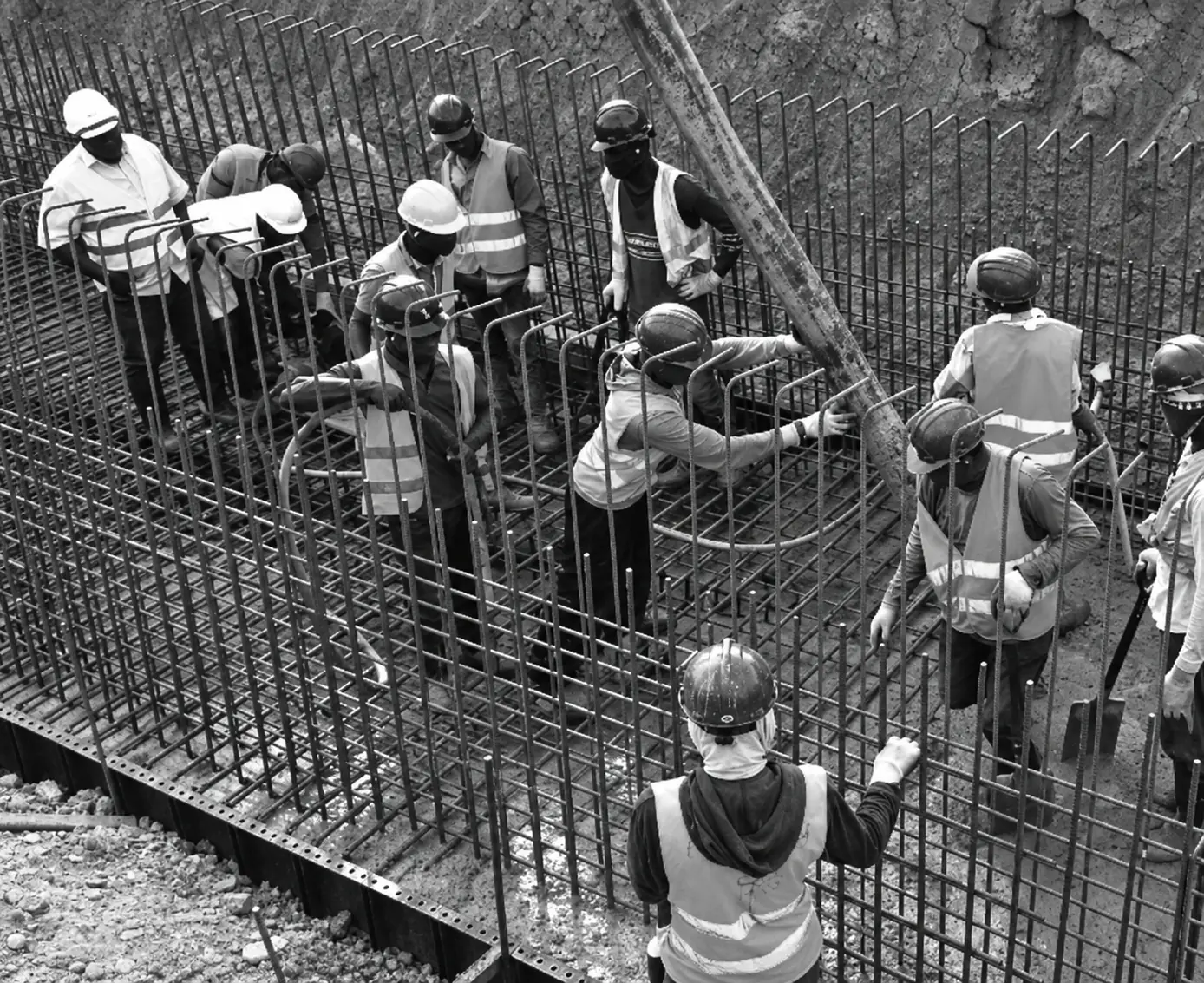 Construction workers in hard hats working together on steel reinforcement at a building site