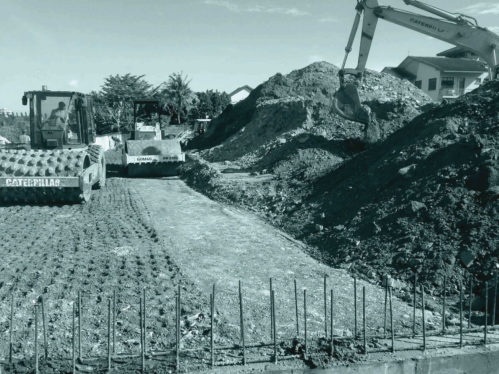 Two compaction rollers and an excavator carrying out groundworks on a construction site